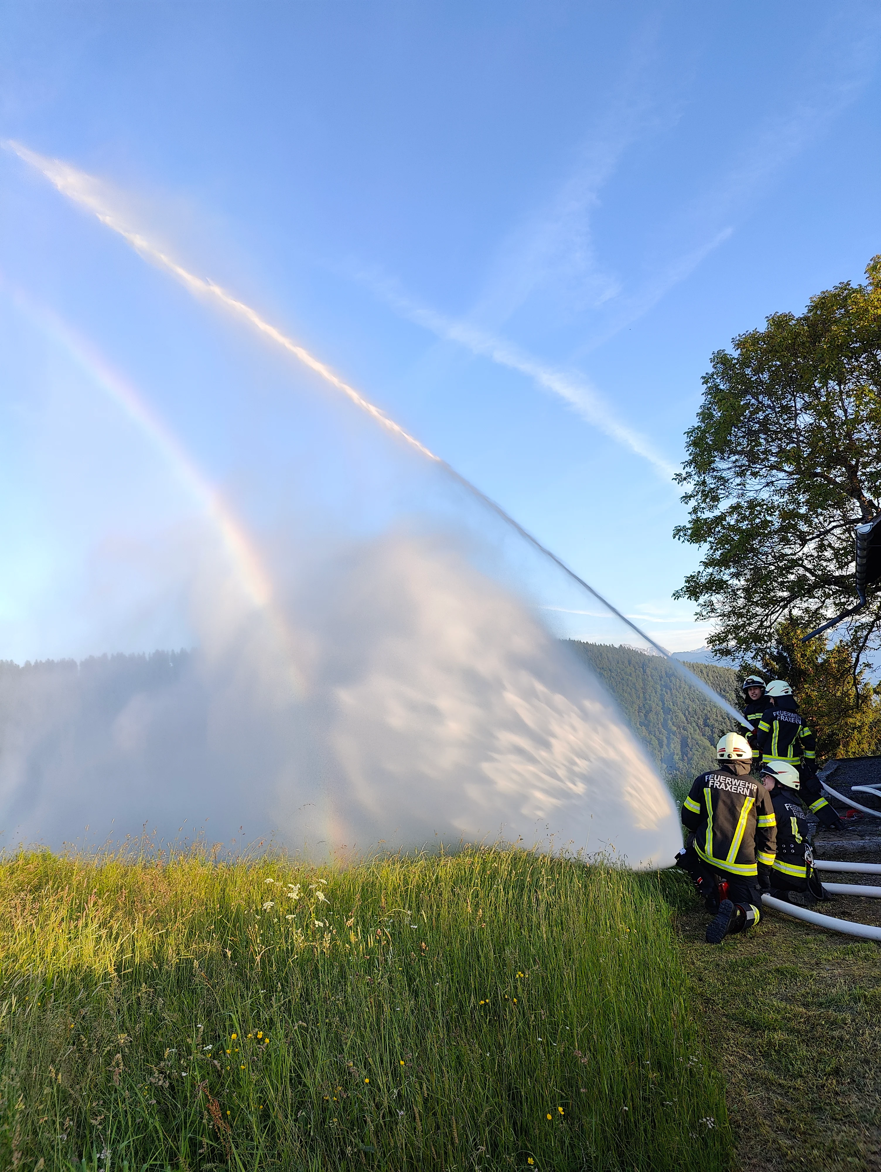 Löschübung: Wasserstrahl mit Regenbogen über der Wiese