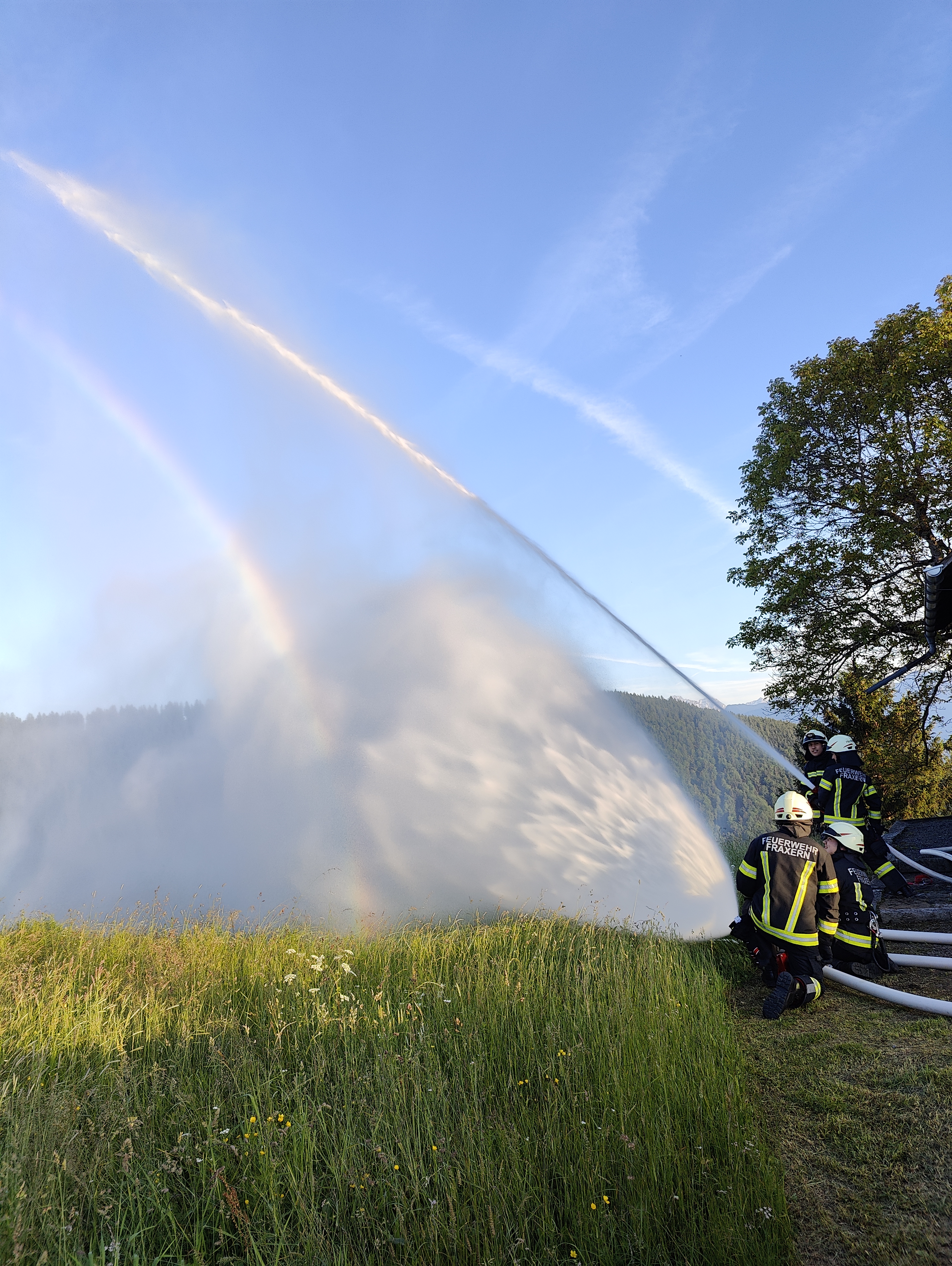 Löschübung: Wasserstrahl mit Regenbogen über der Wiese